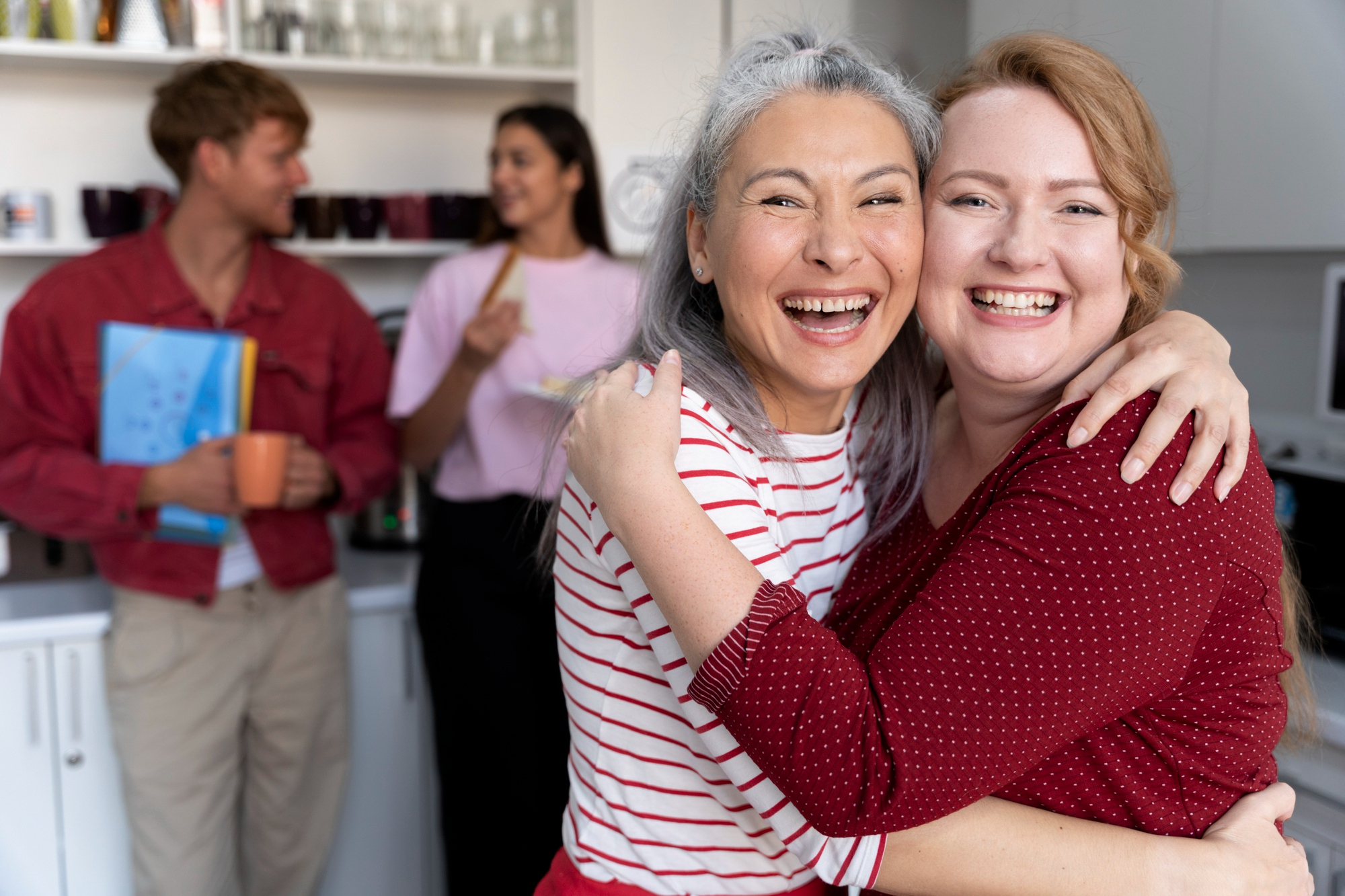 Senior residents smiling with care providors in the background.