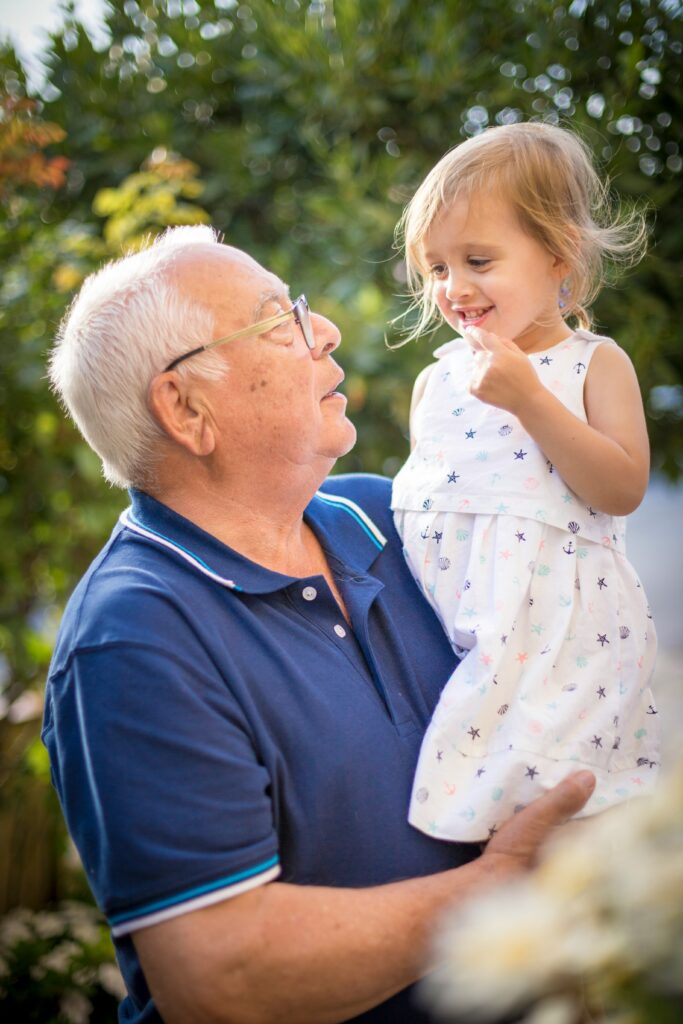 A senior holding his grandchild and smiling together