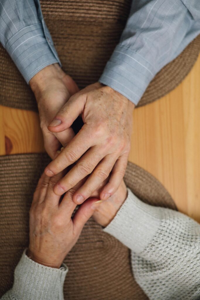 A senior couple holding hands on a table.